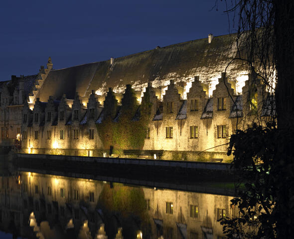 Warm wit verlichte trapgevels van het Groot Vleeshuis in Gent bij valavond