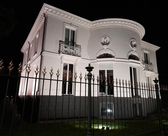 Illuminated white façade of the villa with semi-circular extension in the Lousberg Park in Ghent
