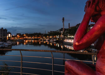 Red statue of a lady along the water of the Portus Ganda marina in Ghent