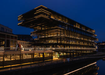 The lit library building 'De Krook' at falling evening