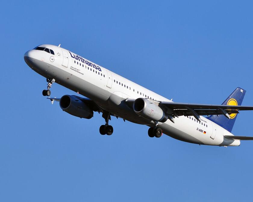 A Lufthansa-plane taking off into a clear blue sky.