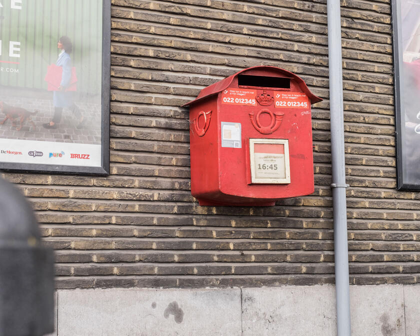 Un buzón de correos colgando en una pared de ladrillos. 