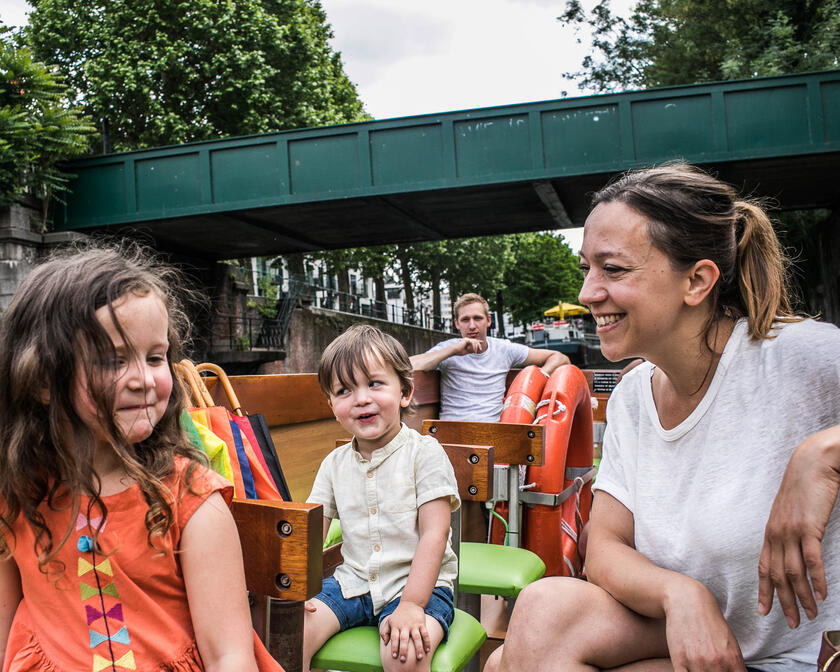 Moeder, dochter, zoon en vader zitten in een boot, aan het varen door het centrum van Gent.