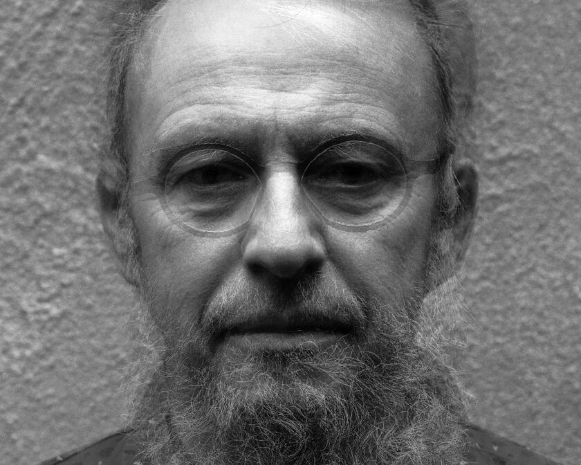 zwart-wit foto van een man met een baard en een bril en een hemd aan