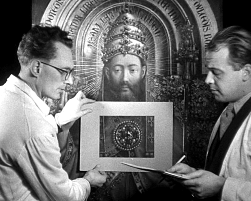 2 mannen die voor een schilderij staan, de ene houdt een papier vast met een gat erin, de ander bladeren en een stylo