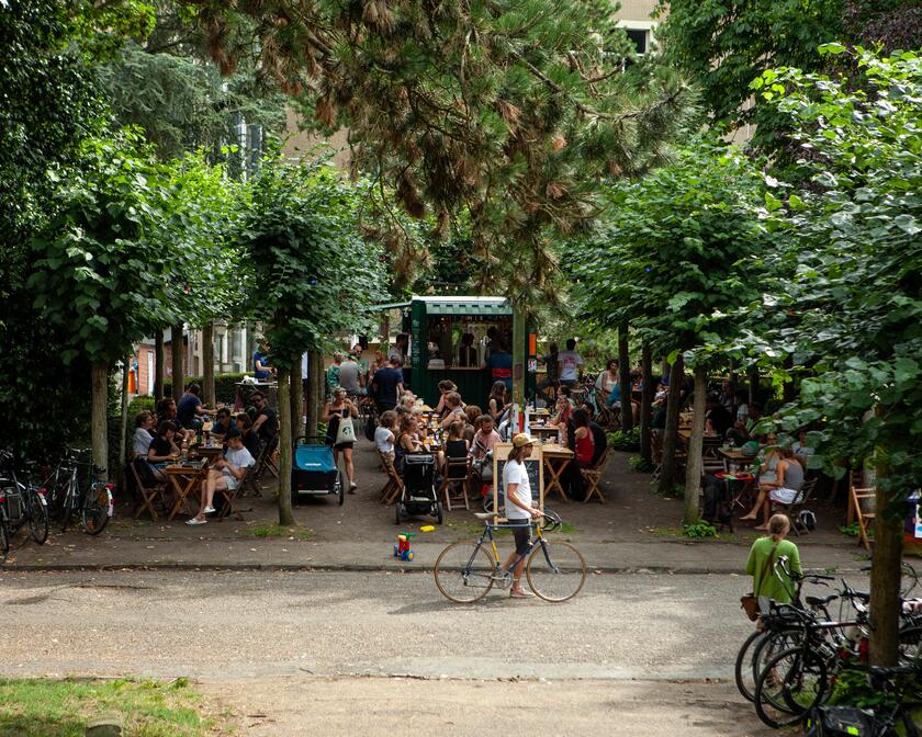 mensen die op een terras zitten tussen de bomen, verschillende fietsen