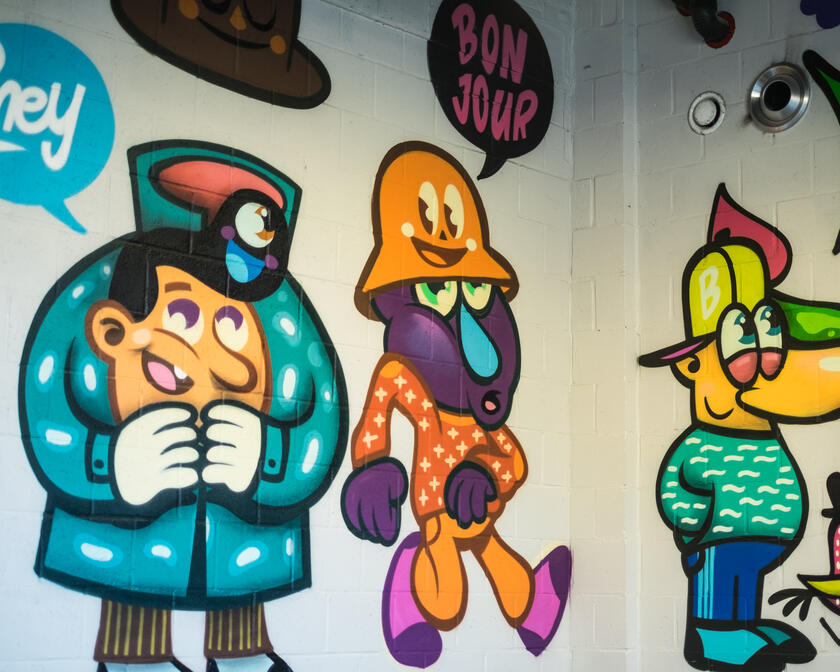 Kleurrijke animatiefiguren op een witte muur met graffiti.