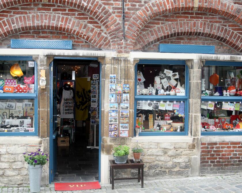 Etalage en inkomdeur van klein winkeltje met postkaarten en snuisterijen.