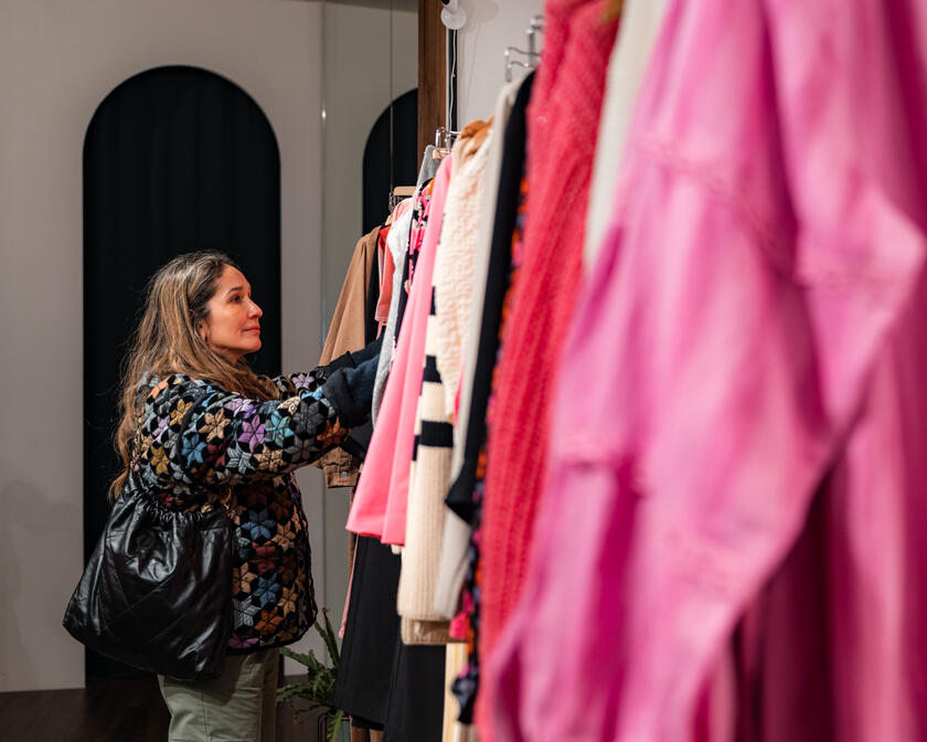 ©PuurGent Tiany kijkt naar kleding aan kledingrek tijdens het shoppen
