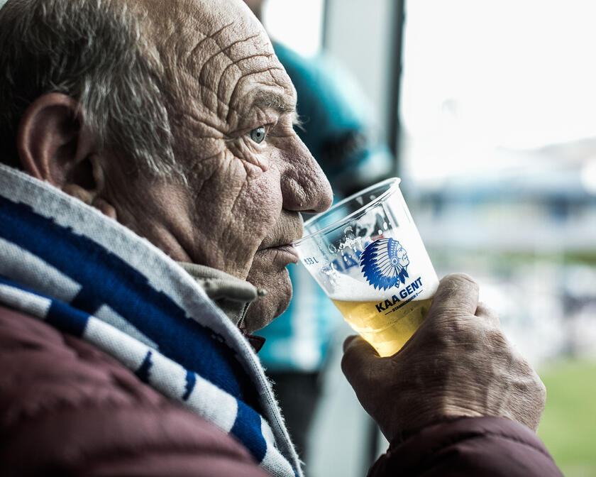 El hombre bebe cerveza durante el partido de fútbol en el Ghelamco Arena