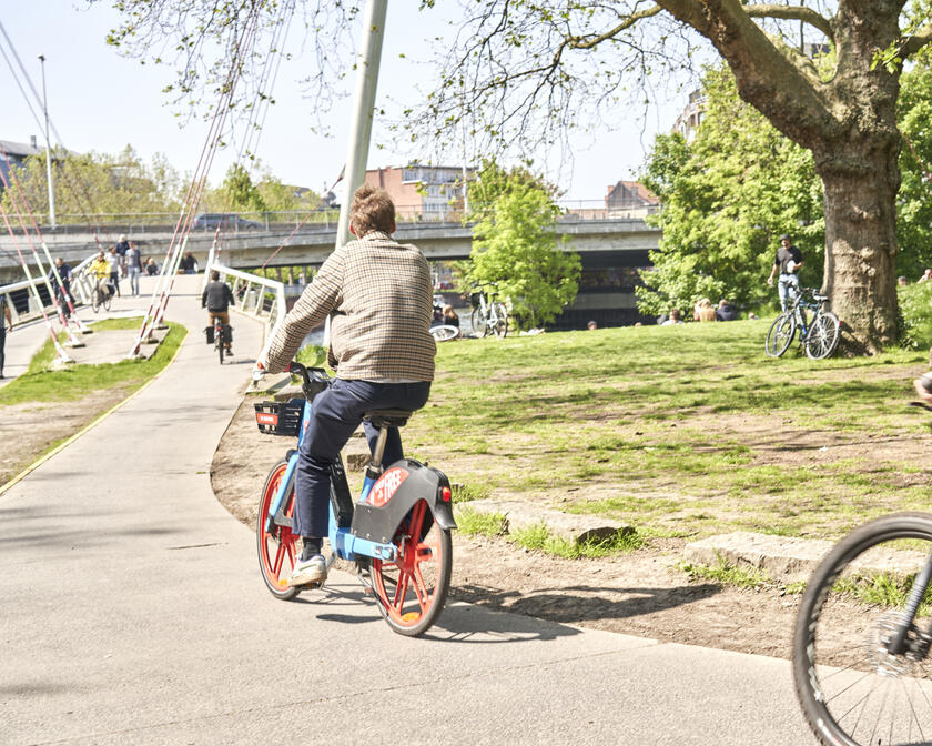 Two cyclists ride to the bicycle bridge in the Keizerspark in Ghent on a beautiful sunny day