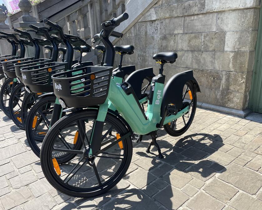 5 green parked Bolt bikes on a sunny day