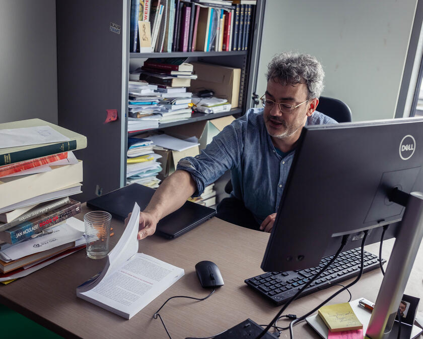 Professor Jan Dumolyn shows book in his office at Ghent University