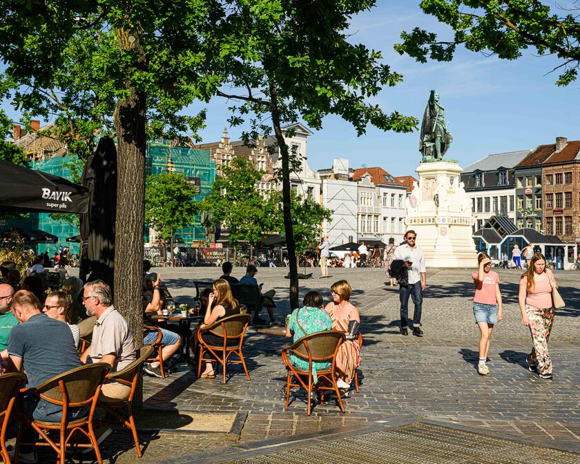 Mensen op een terras in de zon aan de Vrijdagmarkt