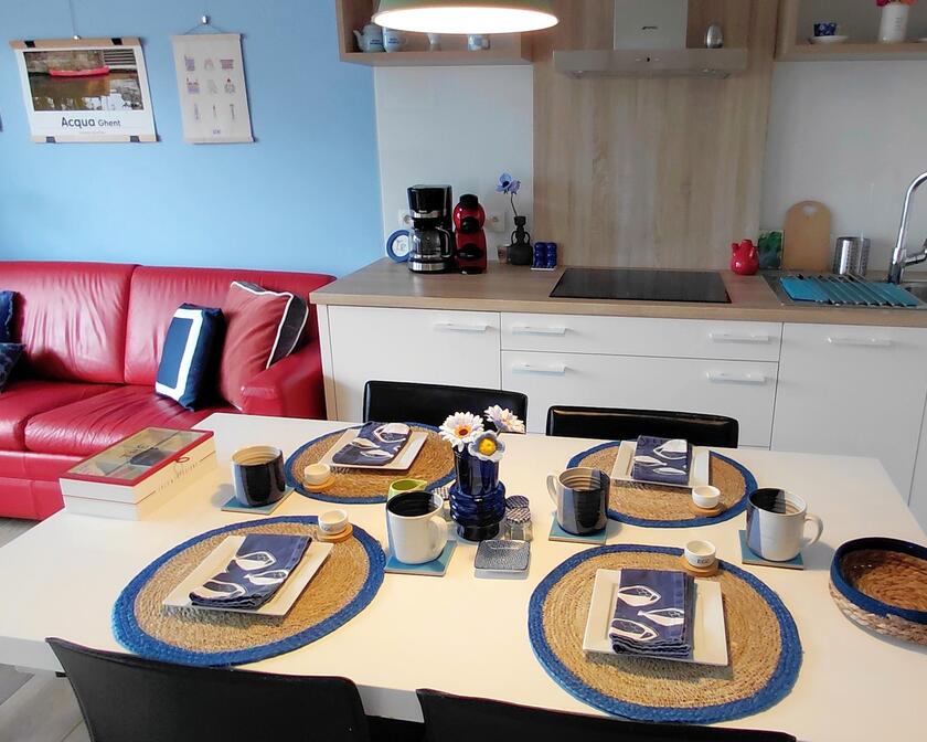 Open ruimte met zitgedeelte links en keuken met tafel rechts