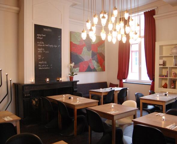 Strak interieur met houten tafels en zwarte stoelen, rode gordijnen.