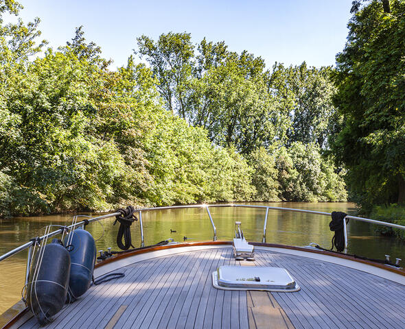 het voordek van een boot op het water tussen het groen