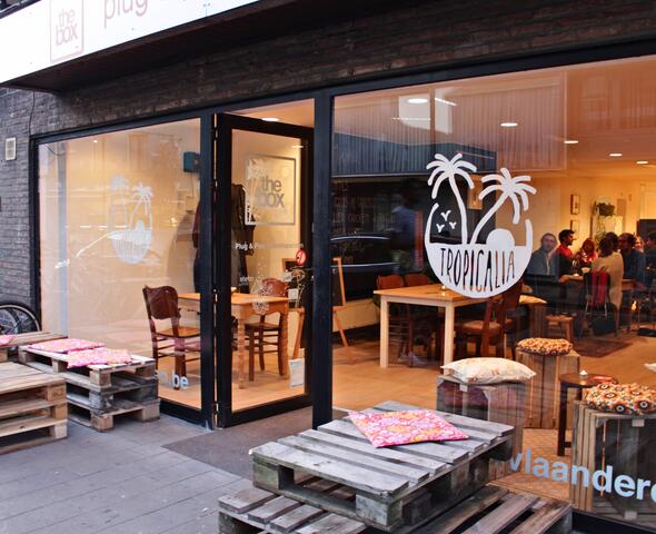 Houten buitenterras van Tropicalia met een glimp van het interieur met klanten.