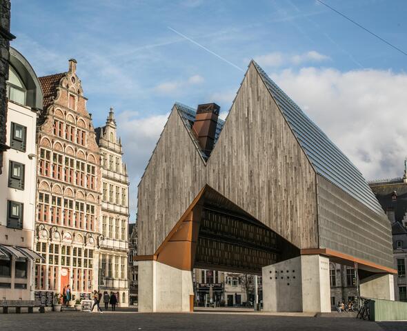De stadshal gebouwd uit hout, beton en glas en omringd door oude gebouwen met getrapte daken. 
