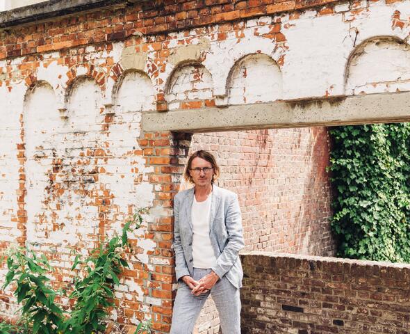 Ignaas Devisch in front of a red brick wall with a hole in