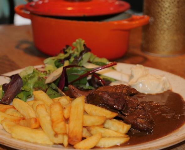 een bord met stoverij, frieten en een salade