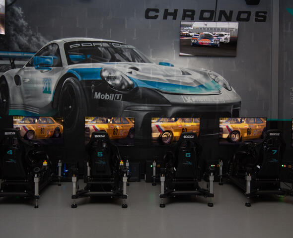 4 racestoelen voor een tv-scherm , een raceauto op de muur