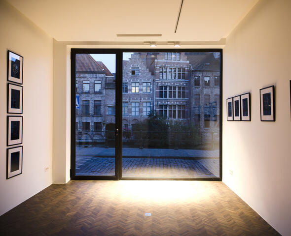 kamer met foto's aan de muren, ramen die uitkijken op de straat