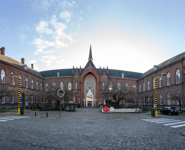 le bâtiment KASK, grand bâtiment en briques, devant lequel se trouvent des passages pour piétons avec des lampadaires jaune-noir