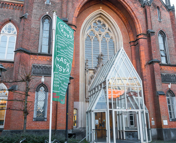 voorkant ingang KASK, glazen constructie voor de ingang, groene vlag met KASK op, fietsen 