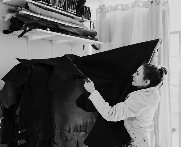 Griet laughs exuberantly as she hangs her pieces of leather on the leather rack.