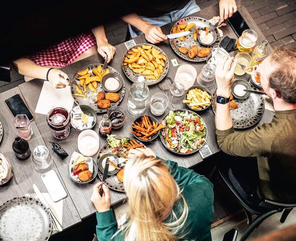 tafel van 4 met allerlei bordjes met kroketjes, frietjes en salades