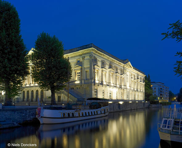 Verlicht Oud-Justitiepaleis met weerspiegeling op het water in Gent