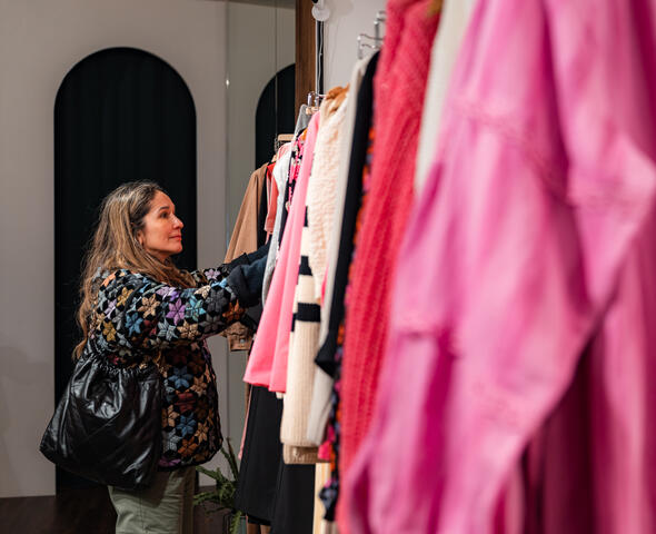 Tiany kijkt naar kleding aan kledingrek tijdens het shoppen