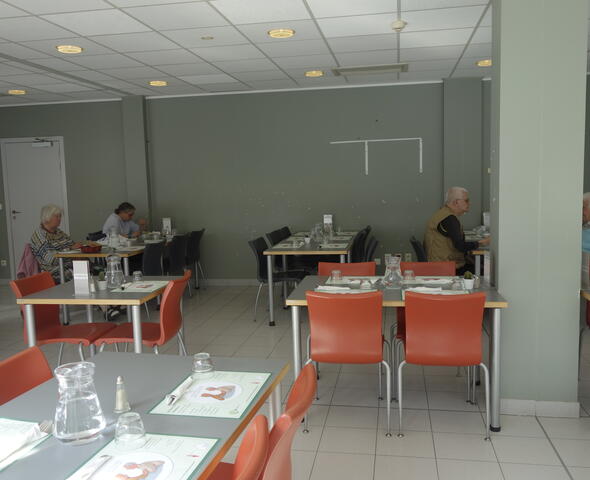 witte eetzaal met witte tafels en oranje stoelen