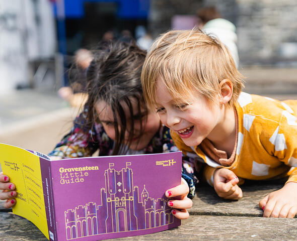 2 kindjes kijken in het Little Guide boekje van het Gravensteen