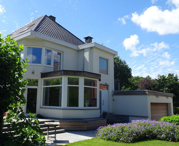 zicht op de witte villa met orangerie vanuit de tuin