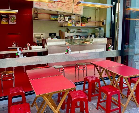 terras met rode stoelen en tafels voor het grote raam van het restaurant