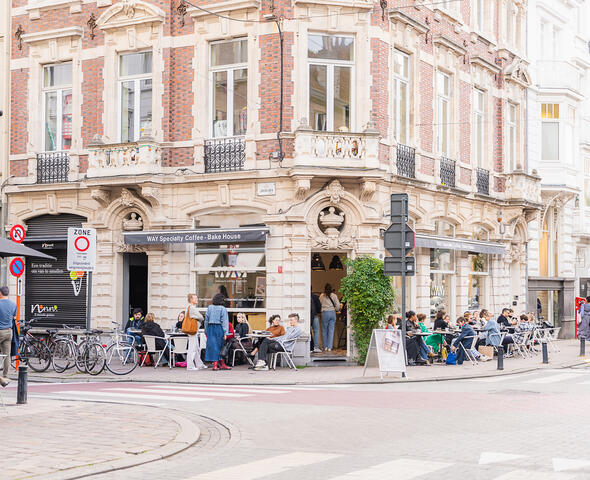Mensen zitten gezellig op terrasje in winkelstraat in Gent