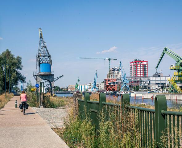 fietser op fietspad langs de oude dokken met kranen op de achtergrond