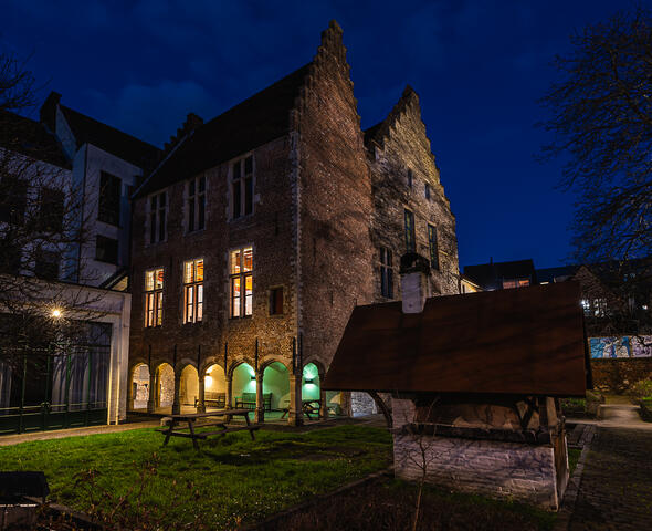 De verlichte gebouwen van het Hof van Ryhove bij donkerblauwe avondhemel