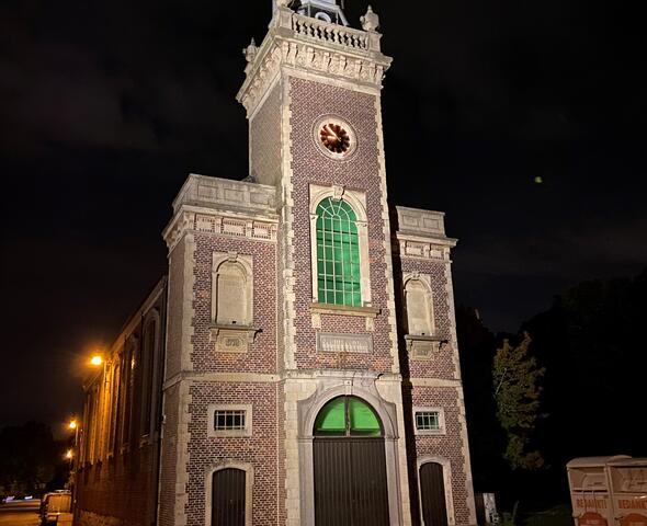 Iglesia iluminada con una esbelta fachada y una torre por la noche en Meulestede