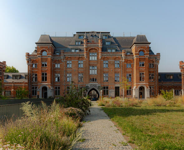 View from the courtyard garden of a large brick building with a slate roof