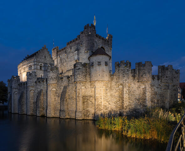 Castillo gris con iluminación blanca cálida a lo largo del paseo marítimo
