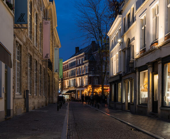Estrecha calle comercial con escaparates iluminados al atardecer