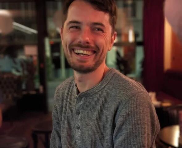 man met baardje lacht naar de camera