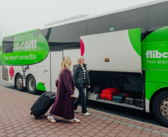 Dos personas con equipaje suben a un autobús de Flibco.