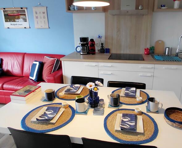Open ruimte met zitgedeelte links en keuken met tafel rechts