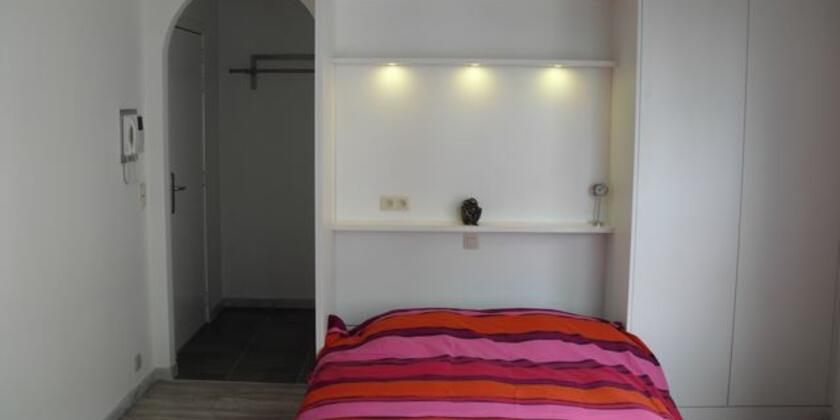 Wit wandmeubel met kleurig opgemaakt dubbel bed.