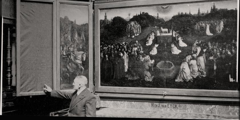 zwart-wit foto van man die naar missend paneel van het Van Eyck schilderij wijst 