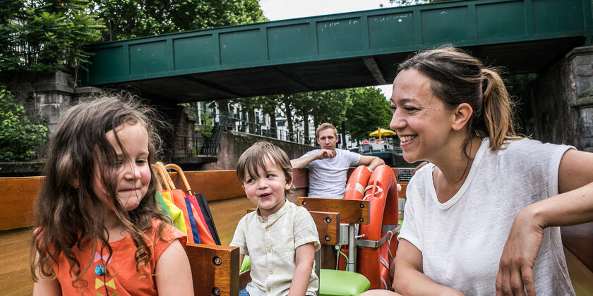Moeder, dochter, zoon en vader zitten in een boot, aan het varen door het centrum van Gent.